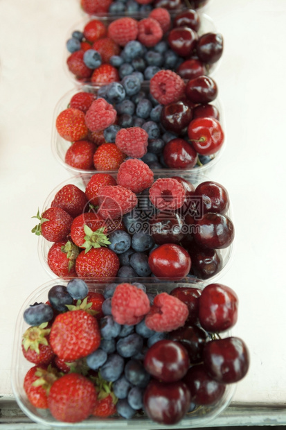 新鲜的草莓樱桃蓝在盒子上市场的图片
