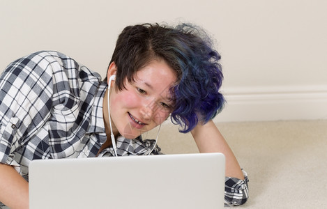 微笑的少女看着电脑一边听家里的音乐图片