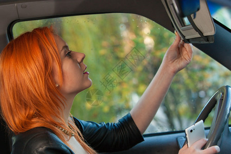 忙着看镜子的女人开车时用电话图片