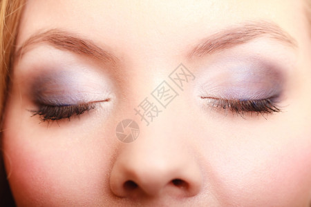 美女双眼的近相蓝色紫的化妆品将涂在眼睛上图片