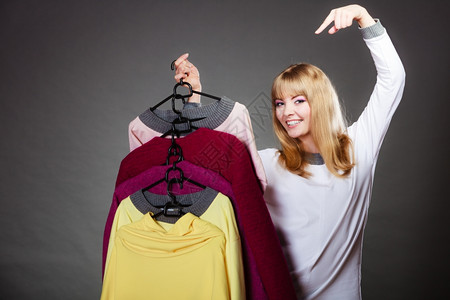 简洁衣柜零售和销金发美女时装服顾客与衣着多彩灰色背景的手指衣架
