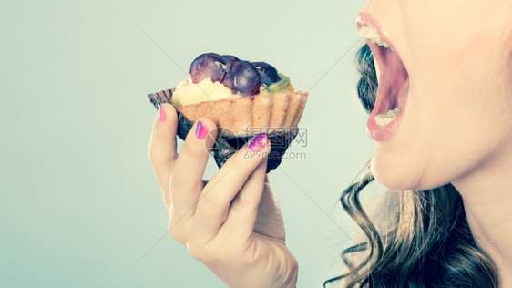 甜美的食物浸泡和脂肪的概念妇女面对张开的嘴吃蛋糕用过滤的照片图片