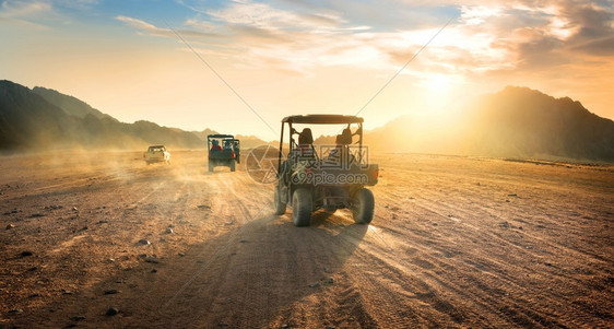日落时在沙漠中行驶的汽车群图片