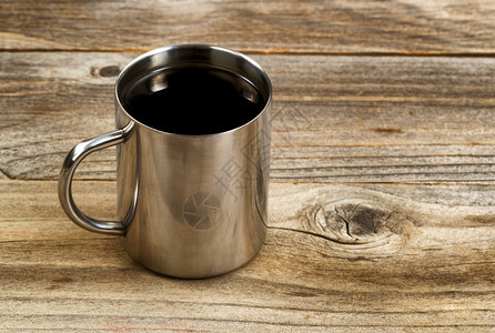 选择地关注不锈钢咖啡杯嘴唇在生锈木材上采用横向形式图片