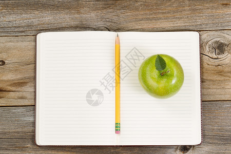 绿色苹果的顶端景用铅笔打开记本中间在生锈的木头上图片