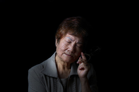 年长妇女拿着黑色背面的阅读杯表现出疼痛图片