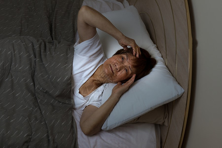 高龄女在夜里盯着卧室的天花板看失眠的概念图片