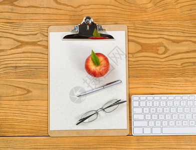 剪贴板计算机键盘阅读眼镜苹果纸和在桌面上的顶端视图图片