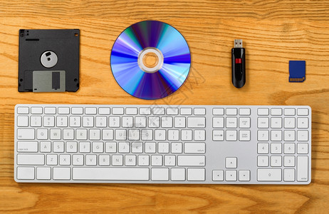 用键盘软CD拇指驱动器和闪存盘对桌面的顶端视图带有技术变化的便携式数据存储装置的概念图片