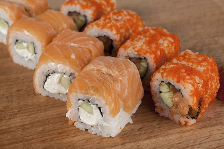 美味的日本新鲜寿司卷配有鲑鱼奶酪加州飞鱼红子酱芥木板上的芥子酱图片