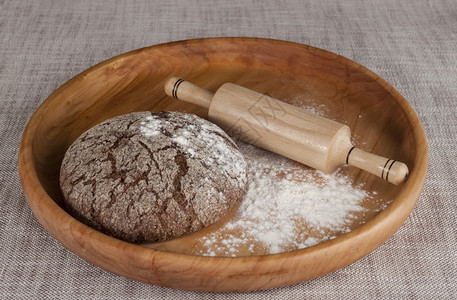 新鲜自制面包用双麦成黑用滚动针的木盘在美丽的桌布上制成关于烹饪美食的杂志照片图片