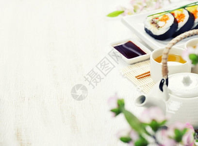 寿司绿茶和竹垫上的樱树枝图片