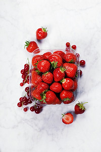 透明塑料托盘配有新鲜采摘的草莓图片