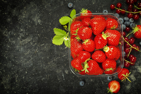 透明塑料托盘配有新鲜采摘的草莓图片
