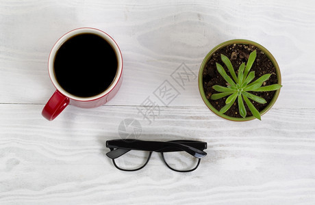 白色桌面有红咖啡杯阅读眼镜和婴儿植物背景图片
