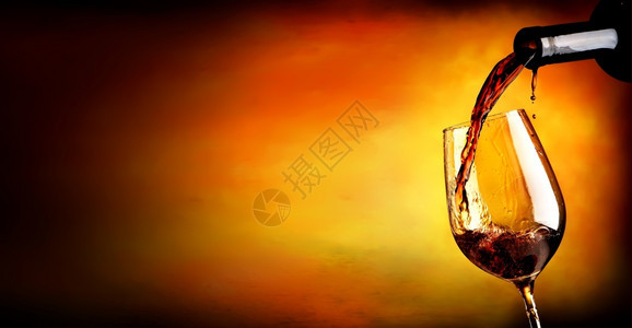 橙色背景的葡萄酒倒在杯中图片
