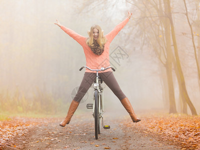 年轻女子在森林公园开心骑着自行车图片