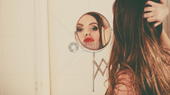 年轻女孩看着镜子年轻女孩在浴室里看着镜子图片