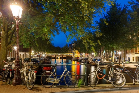 荷兰阿姆斯特丹运河和桥梁船只自行车的夜间城市景色图片