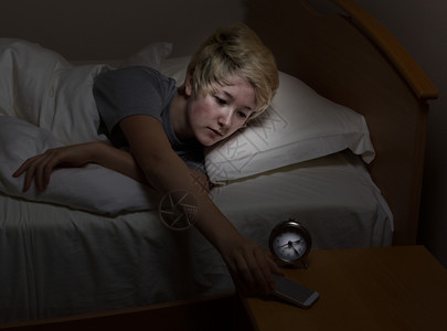 青少年女孩在睡觉时夜间站着床上伸手取她的机青少年在夜间使用技术而不是睡觉图片