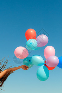 女手拿着彩色气球云的天空背景户外图片