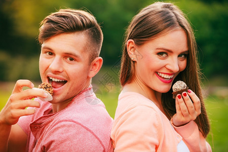 年轻的情侣外出野餐时吃着糖果松饼图片