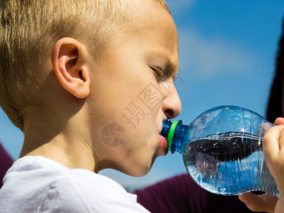 小口渴的男孩儿在户外用塑料瓶喝水背景图片