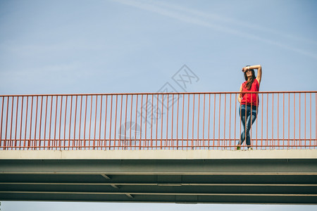长头发的年轻女孩保护着城市大桥的视线夏天生活方式很怪异特伦迪运动少年图片