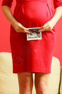 怀孕母亲和幸福穿着优雅红裙子的孕妇近身肚子室内超声波扫描图片
