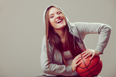 身着运动服的年轻女孩高兴的抱着篮球图片