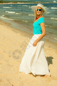 时装幸福和生活方式概念穿着蓝太阳眼镜和夏装在海滩上散步的金发美女在海边放松的年轻女子图片