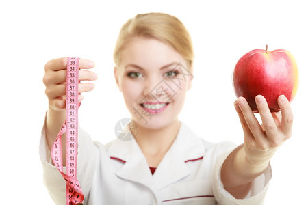 低调饮食概念白大衣上的女人建议健康食物医生专家饮食师拿着水果苹和测量胶带被隔离图片