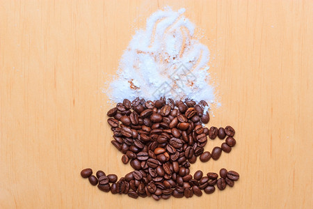 卡布奇诺时间烤咖啡豆以木制表面背景上含肉桂白霜的杯子和碟形式图片