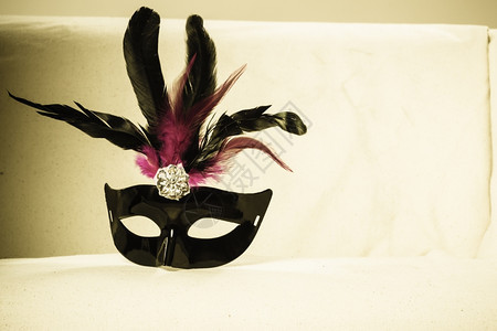 假日和庆祝概念黑粉色狂欢节的花面罩躺在家里的沙发上图片