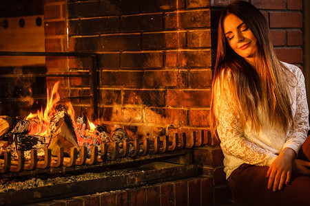 女人在壁炉里放松冬天回家女人在壁炉里休息年轻女孩暖和家里冬天背景图片