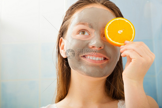 美容护肤化妆品和健康概念戴面部粘土罩的年轻妇女在浴室里用橘子水果切片遮住眼睛图片