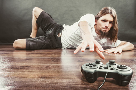 有床位成瘾和依赖概念的年轻人玩游戏的有床杆年轻人男沉迷于控制游戏站的图片