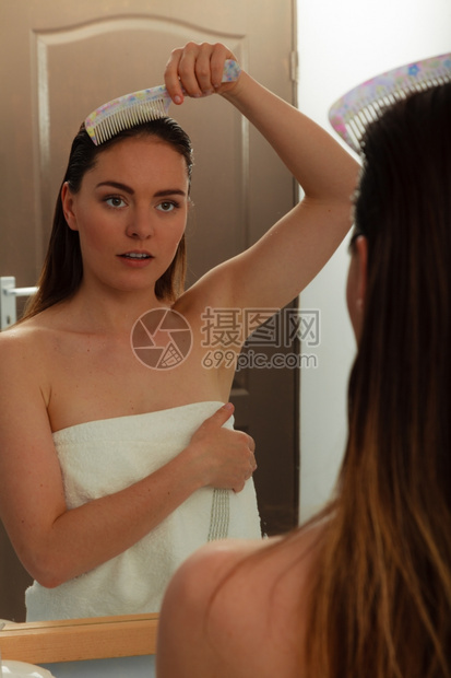 洗完澡后梳湿头发照着镜子看湿头发的女孩浴室卫生图片