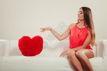 心形枕头的可怜女人情节心形枕头坐在白沙发上的心形枕头不幸年轻女孩情人节的爱图片