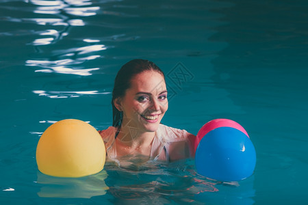 水中快乐的女人玩气球 游泳池水中快乐的女人玩气球 穿着湿白衬衫的少女放松图片
