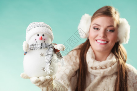 带着小雪人笑的可爱女穿着耳毛和白色衣的迷人女孩穿着绿色工作室图片