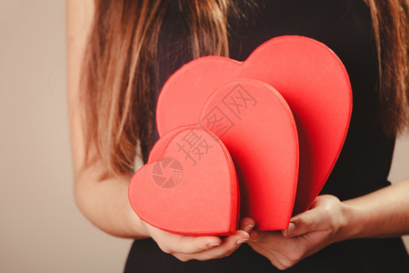 情人节黑衣女子拿着三个红心盒礼物整体优雅的模特配有情人节符号工作室拍的图片