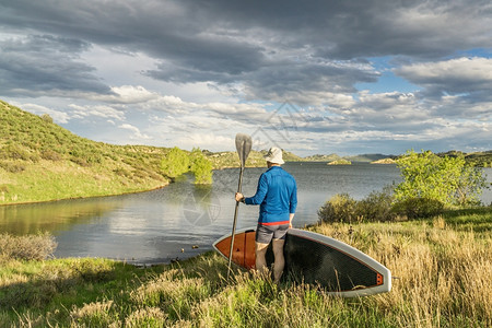 在科罗拉多州柯林斯堡附近山湖草地岸上有起立桨板SUP的男板夫图片