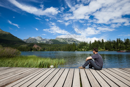 坐在高山湖岸上的人图片