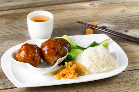 近距离观看亚洲香肠肉丸大米和白盘上的肉酱背景筷子和绿茶图片