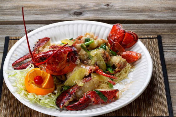 近距离看一整只刚煮熟的缅因州龙虾上面覆满了草药洋葱和白盘上的酱汁图片