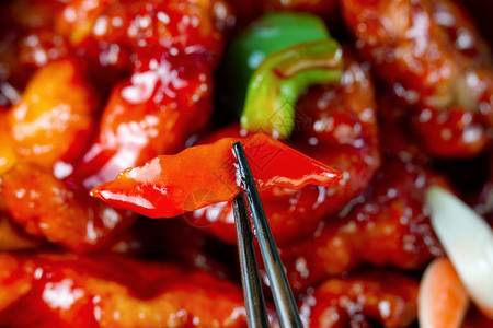 新鲜辣椒和鸡肉加厚酱装满了框架格式有选择地聚焦在筷子之间的正面辣椒上图片