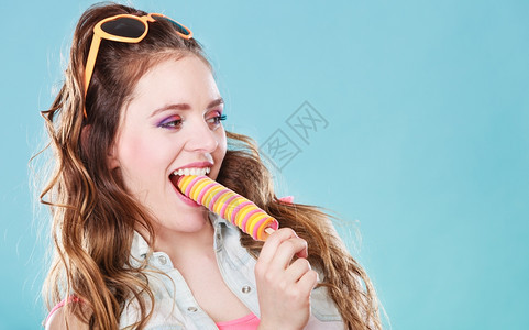 快乐的年轻女模特蓝底吃冰图片