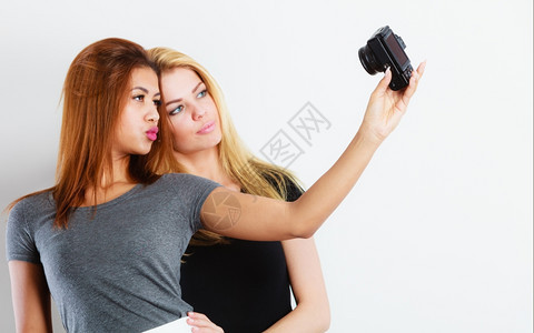 两位美丽的年轻女制作自拍技术互联网和幸福概念金发和混合种族的年轻女用智能手机相拍摄自图片