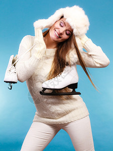 有冰鞋的女人准备去滑冰冬季体育活动穿着温暖衣服的毛和帽微笑女孩在蓝工作室拍摄图片